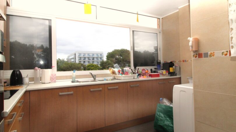 Helle Küche mit Holzunterschränken, Einbauspüle und großem Fenster mit Grün- und Stadtblick in Palma