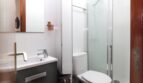 Modernes Badezimmer mit Glasdusche, WC und grauem Waschtisch mit Spiegel in Palma-Wohnung