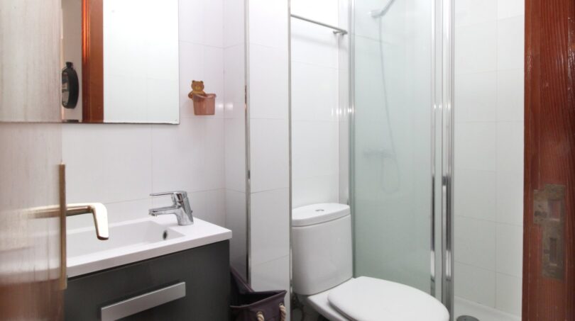 Modernes Badezimmer mit Glasdusche, WC und grauem Waschtisch mit Spiegel in Palma-Wohnung
