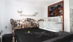 Schlafzimmer mit schwarzem Doppelbett, modeschmuck-Kopfteil, Babybett und offenem Kleiderschrank