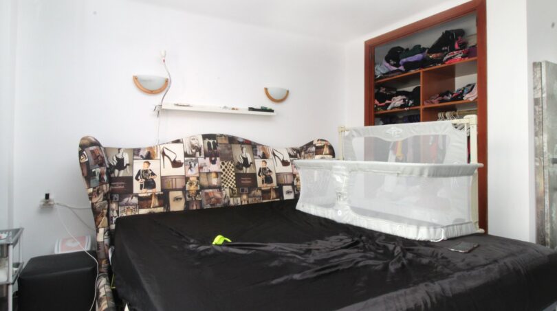 Schlafzimmer mit schwarzem Doppelbett, modeschmuck-Kopfteil, Babybett und offenem Kleiderschrank