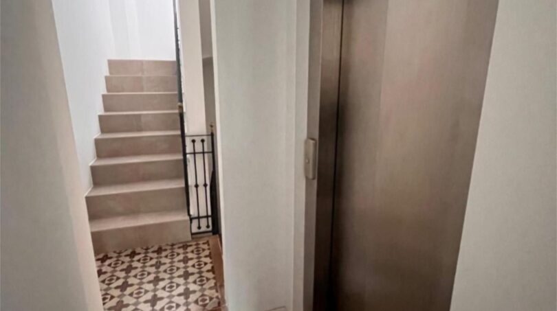 Treppenhaus mit gemusterten Zementfliesen, elegantem Eisengeländer und modernem Aufzug der Maisonette-Wohnung in Palma.