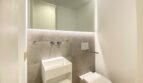 Modernes Gäste-WC der Maisonette in Palma mit beleuchtetem Spiegel, Wandarmatur und schwebender Toilette.