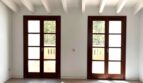 Heller Wohnraum mit zwei Holz-Terrassentüren, weißen Balkendecken und Natursteinboden in Maisonette-Wohnung, Palma