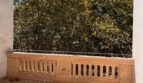 Sonniger Balkon mit dekorativem Steingeländer und üppigem Baumblick der Maisonette-Wohnung in Palma