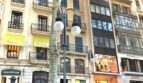 Außenansicht eines eleganten Altbaus in belebter Einkaufsstraße in Palma de Mallorca mit klassischer Fassade und Balkonen.