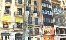 Außenansicht eines eleganten Altbaus in belebter Einkaufsstraße in Palma de Mallorca mit klassischer Fassade und Balkonen.