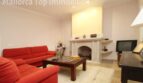 Wohnzimmer der Villa in Alcúdia mit roten Sofas, Steinkamin und TV-Bereich.