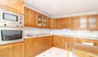 Geräumige Küche der Villa in Alcúdia mit Holzschränken, Einbauofen, Mikrowelle und Esstisch.