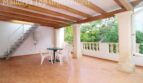 Überdachte Terrasse mit Holzbalkendecke, weißen Gartenmöbeln und Steinbalustrade der Villa in Alcúdia