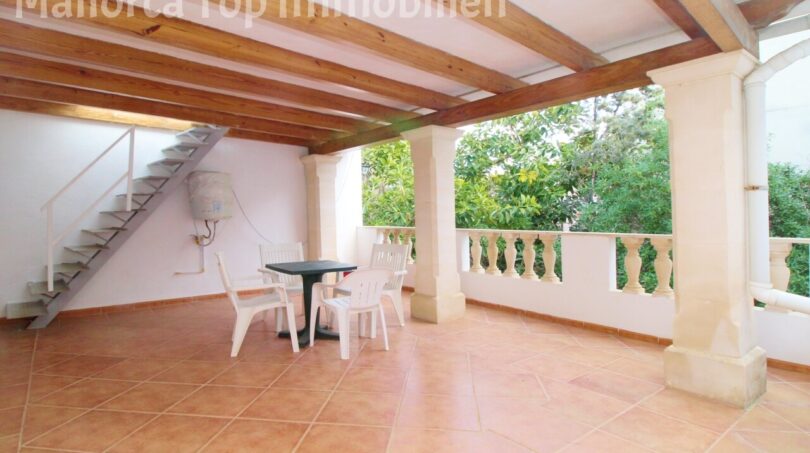 Überdachte Terrasse mit Holzbalkendecke, weißen Gartenmöbeln und Steinbalustrade der Villa in Alcúdia