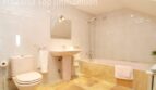 Helles Badezimmer der Villa in Alcúdia mit Badewanne, Dusche, Waschbecken und beigen Fliesen.