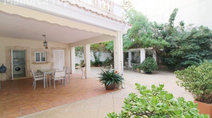 Überdachte Terrasse der Villa in Alcúdia mit Essbereich, Innenhof und üppigem Grün