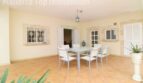 Überdachte Terrasse der Villa in Alcúdia mit Esstisch, Terrakottaboden und Blick ins Innere.