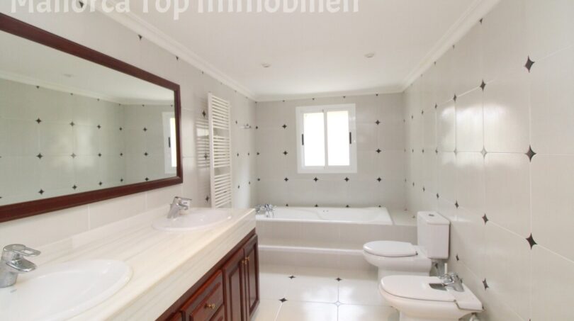 Geräumiges Villenbad mit Doppelwaschbecken, Badewanne, Bidet und WC, helle Fliesen mit Sternmuster.