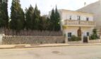 Außenansicht einer mediterranen Villa in Alcúdia mit Balkon, Natursteinmauer und Zypressen nahe Hafen.
