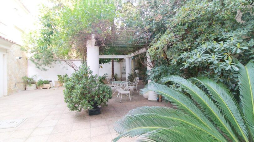 Idyllischer Innenhof der Villa in Alcúdia mit weißen Gartenmöbeln, Palmen und üppigem Grün.