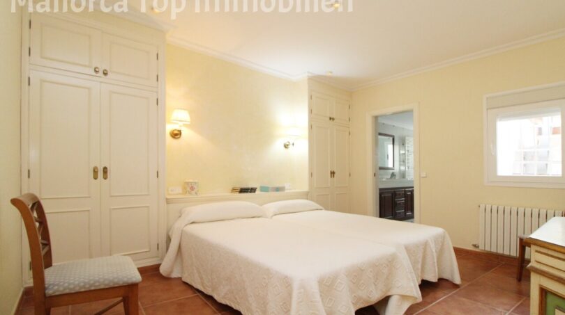 Helles Schlafzimmer der Villa in Alcúdia mit Doppelbett, Einbauschränken und angrenzendem Bad.
