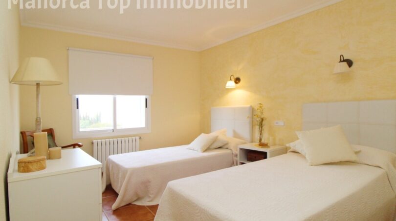 Helles Schlafzimmer der Villa in Alcúdia mit zwei Einzelbetten, gelben Wänden und Terrakottaboden.