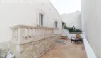 Terrasse der Villa in Alcúdia mit Steinbalustrade, Terrakottaboden und Wicker-Stuhl, nahe Hafen.