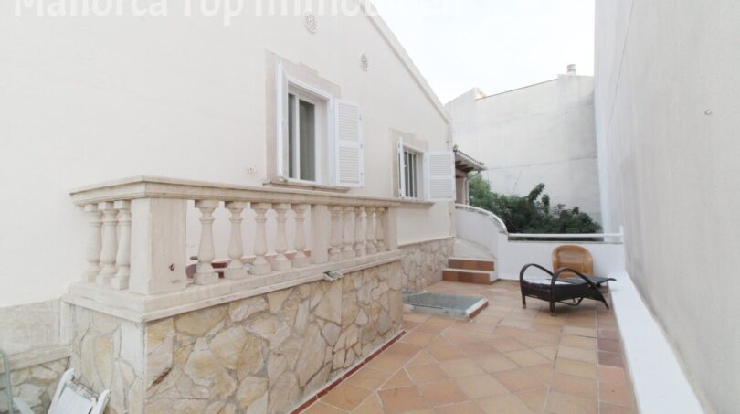 Terrasse der Villa in Alcúdia mit Steinbalustrade, Terrakottaboden und Wicker-Stuhl, nahe Hafen.