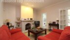 Wohnzimmer der Villa in Alcúdia mit roten Sofas, Kamin und Durchgang zur Küche