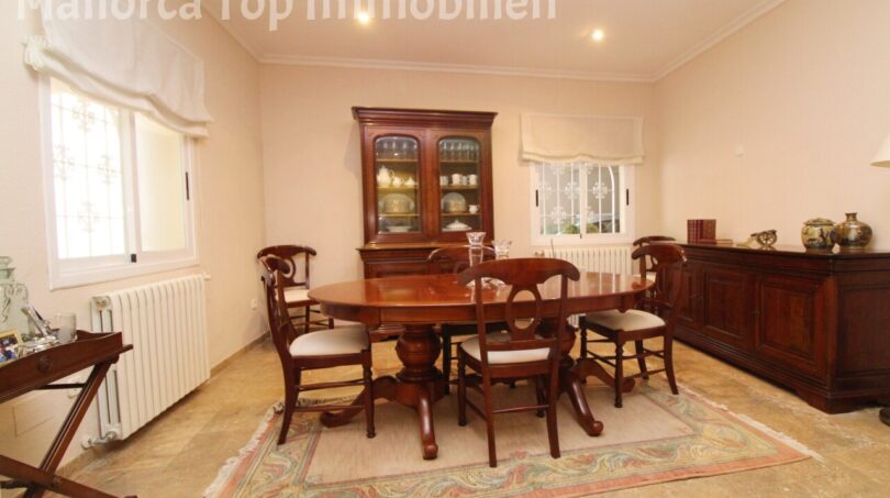Elegantes Esszimmer der Villa in Alcúdia mit Mahagoni-Tisch, Vitrine und Sideboard auf Natursteinboden.