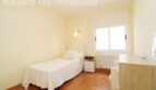 Helles Schlafzimmer der Villa in Alcúdia mit Einzelbett, Nachttisch, Heizkörper und Fenster.