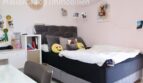 Jugendzimmer mit großem Boxspringbett, grauem Polsterkopfteil, Schreibtisch und Klimaanlage in Doppelhaushälfte Llucmajor