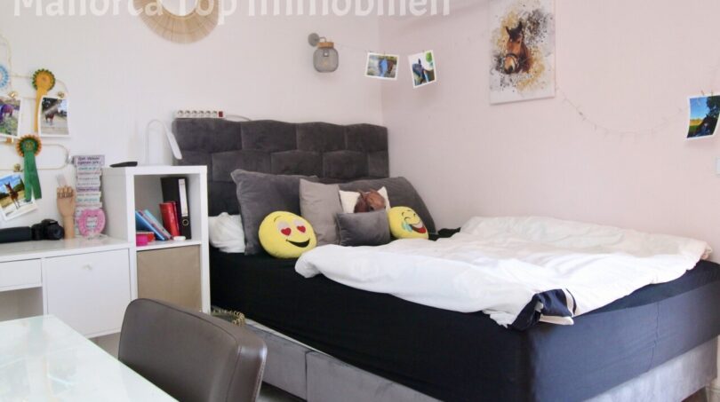 Jugendzimmer mit großem Boxspringbett, grauem Polsterkopfteil, Schreibtisch und Klimaanlage in Doppelhaushälfte Llucmajor