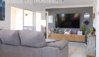 Helles Wohnzimmer mit grauem Sofa, großem TV und modernem Holz-Sideboard in Doppelhaushälfte Llucmajor