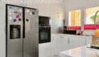 Moderne weiße Küche mit LG Side-by-Side-Kühlschrank, Einbauofen und Fenster zur Terrasse in Doppelhaushälfte Llucmajor
