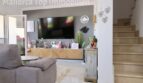 Wohnzimmer der Doppelhaushälfte in Llucmajor mit TV-Wand, Holzkommode und Treppenaufgang
