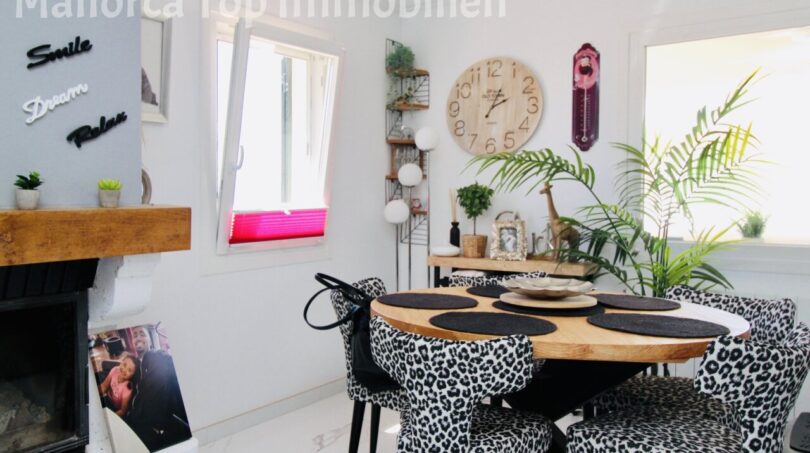 Helles Esszimmer mit rundem Holztisch, Leoparden-Stühlen und Kamin in Doppelhaushälfte in Llucmajor