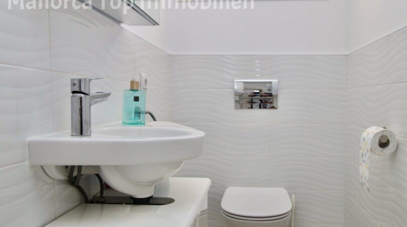 Modernes weißes Gäste-WC mit Wandhänge-WC, kleinem Waschbecken und Chromarmaturen in Doppelhaushälfte Llucmajor