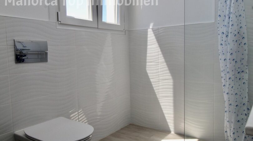 Modernes Badezimmer mit Wandhänge-WC, Dusche und weißen Strukturfliesen in Doppelhaushälfte Llucmajor