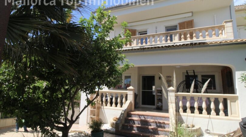 Außenansicht Doppelhaushälfte Llucmajor mit Balkon, Terrasse, Treppenaufgang und mediterranem Garten mit Palmen.