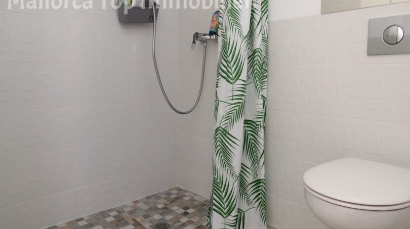 Modernes Badezimmer mit bodenebener Dusche, tropischem Duschvorhang und Wand-WC in Doppelhaushälfte Llucmajor