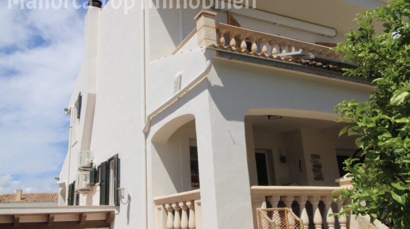 Außenansicht der modernen Doppelhaushälfte in Llucmajor mit weißer Fassade, Balkon und überdachter Terrasse.