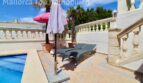 Sonnige Poolterrasse der Doppelhaushälfte in Llucmajor mit Liegestühlen, Sonnenschirm und weißer Balustrade