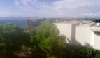 Vista panorámica del terreno para construir a la bahía de Palma con pinos y edificio blanco en Llucmajor
