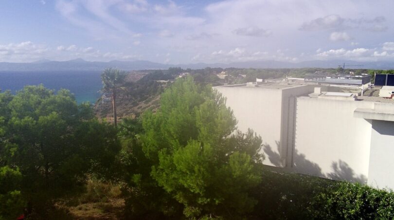 Vista panorámica del terreno para construir a la bahía de Palma con pinos y edificio blanco en Llucmajor