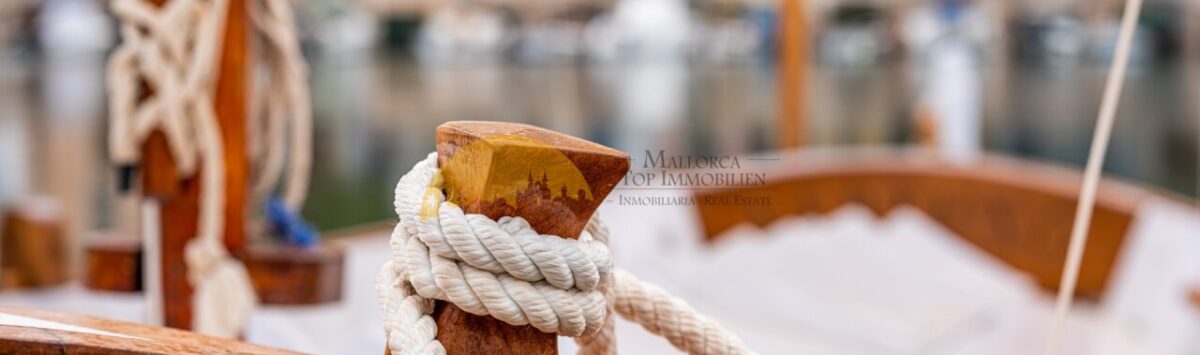 Holzboot mit Tauwerk im Hafen von Cala Pi, nahe modernem Reihenhaus mit Meerblick in Llucmajor.