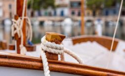 Holzboot mit Tauwerk im Hafen von Cala Pi, nahe modernem Reihenhaus mit Meerblick in Llucmajor.