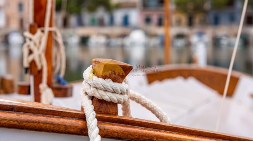 Holzboot mit Tauwerk im Hafen von Cala Pi, nahe modernem Reihenhaus mit Meerblick in Llucmajor.