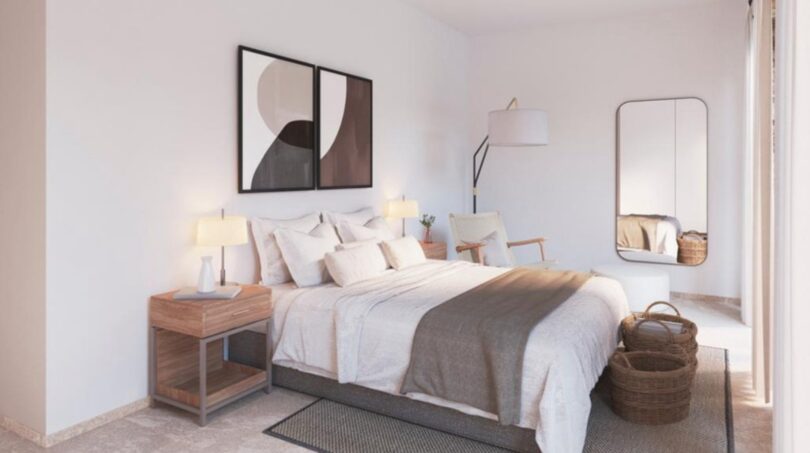 Helles Schlafzimmer der Neubau-Finca in Manacor mit Doppelbett, Holzmöbeln und modernem Wandspiegel