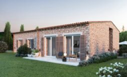 Vista exterior de la nueva Finca Manacor: Villa de piedra natural con terraza, persianas de madera y jardín bien cuidado de estilo mediterráneo.