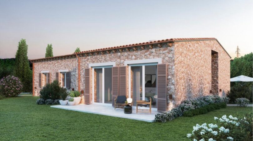 Vista exterior de la nueva Finca Manacor: Villa de piedra natural con terraza, persianas de madera y jardín bien cuidado de estilo mediterráneo.