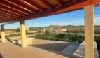 Überdachte Terrasse mit Holzbalkendecke, Blick auf Pool, Grünflächen und Hügel der Finca in Manacor
