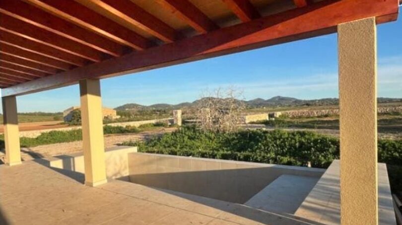 Überdachte Terrasse mit Holzbalkendecke, Blick auf Pool, Grünflächen und Hügel der Finca in Manacor